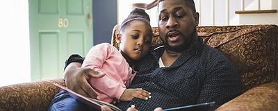 Father reading to his daughter at home.