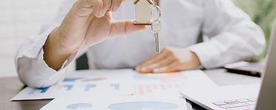 Person holding a house key with charts on the table.