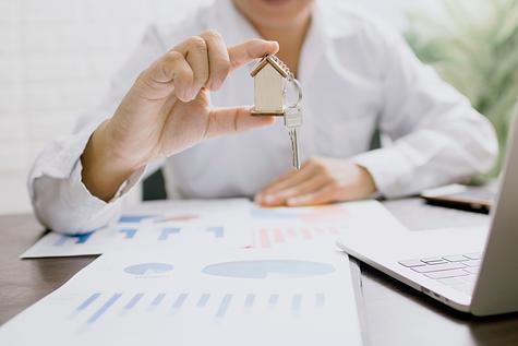Person holding a house key with charts on the table.