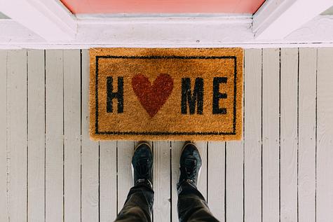 Welcome mat with a heart, symbolizing the benefits and emotional value of buying a home.