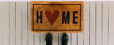 Welcome mat with a heart, symbolizing the benefits and emotional value of buying a home.