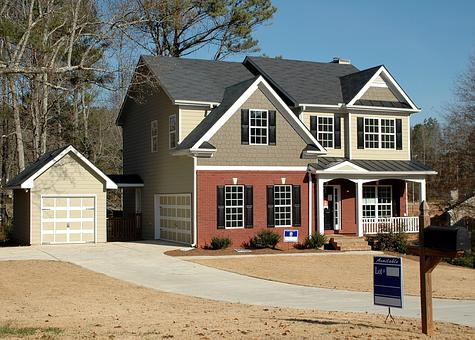Two-story house with a for-sale sign.