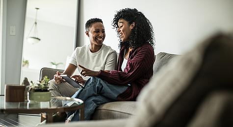 Happy couple discussing home buying strategies while sitting on a couch.