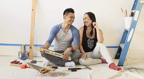 Couple sitting on the floor with renovation tools.