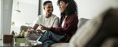 Happy couple discussing home buying strategies while sitting on a couch.