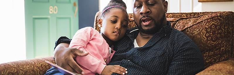 Father reading to his daughter at home.