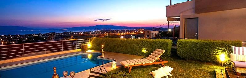 Luxurious vacation home with a pool and scenic view at sunset.