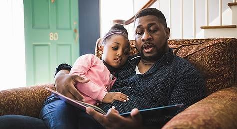 Father reading to his daughter at home.