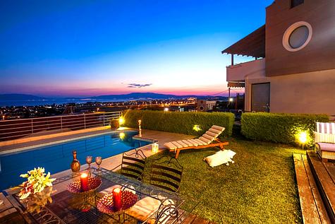 Luxurious vacation home with a pool and scenic view at sunset.