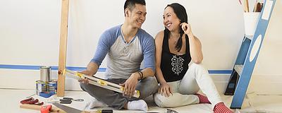 Couple sitting on the floor with renovation tools.