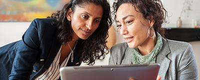 Two women reviewing home pricing strategies on a tablet.