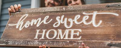 Couple holding a ‘home sweet home’ sign.